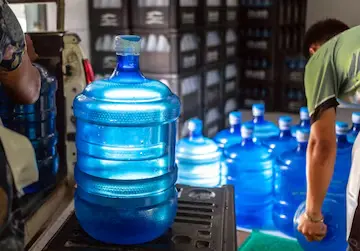 Warehouse worker handling large blue water bottles